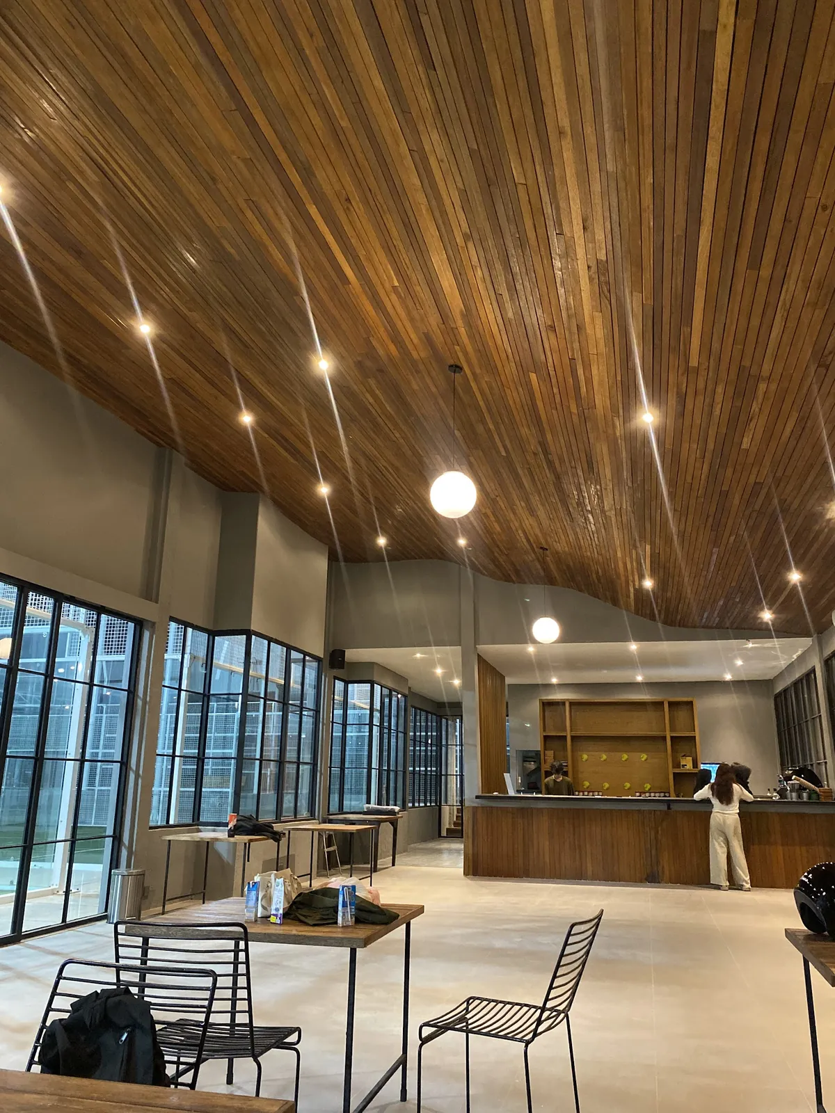 Ella Café's open room with a slatted timber ceiling, pendant lights and black-framed windows