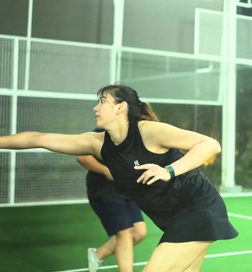 A player in black stretching for a forehand on Ella's green court